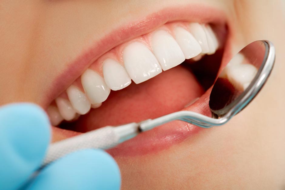 Close-up of patient’s open mouth during oral checkup with mirror near by